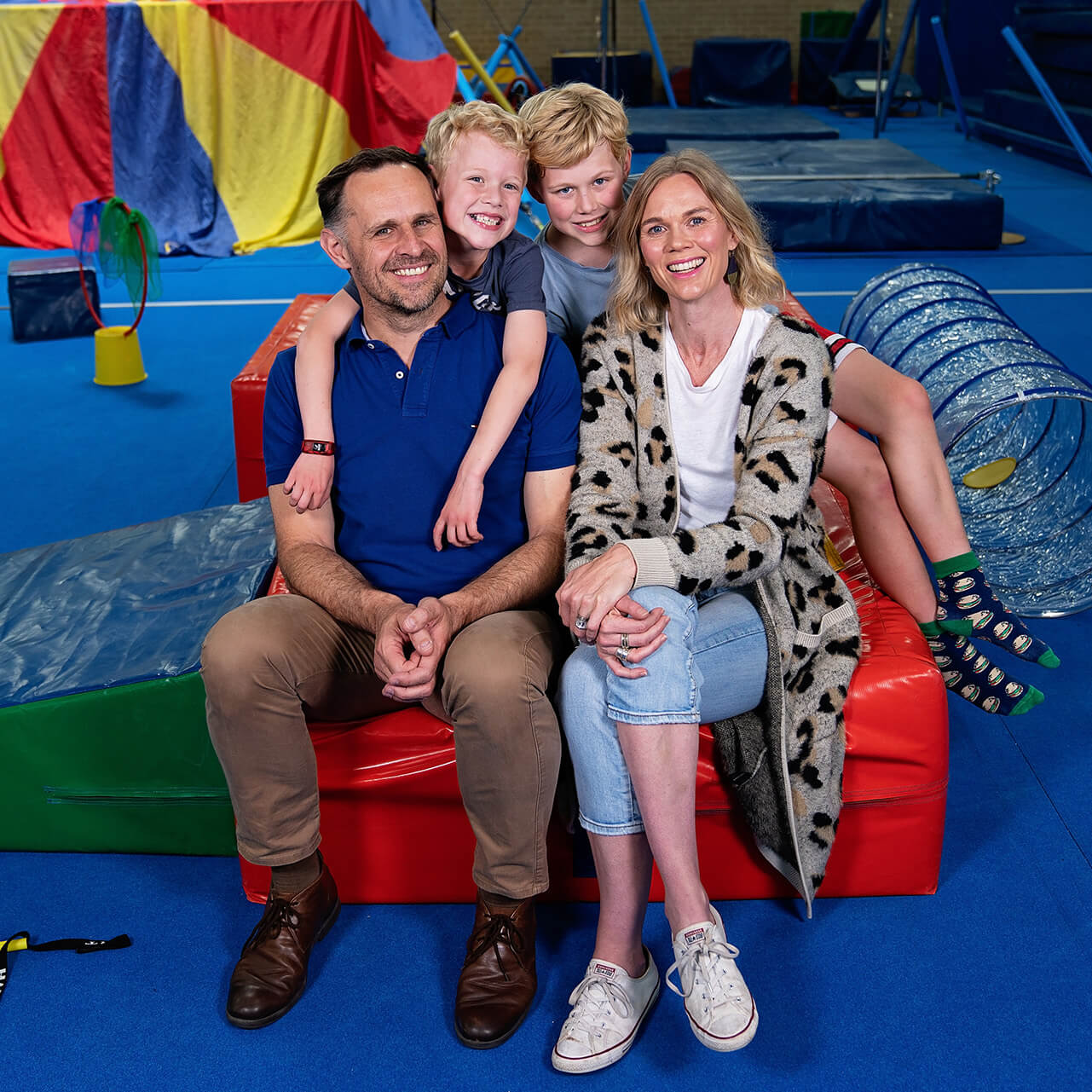 A family who attend KinderGym sitting together and smiling