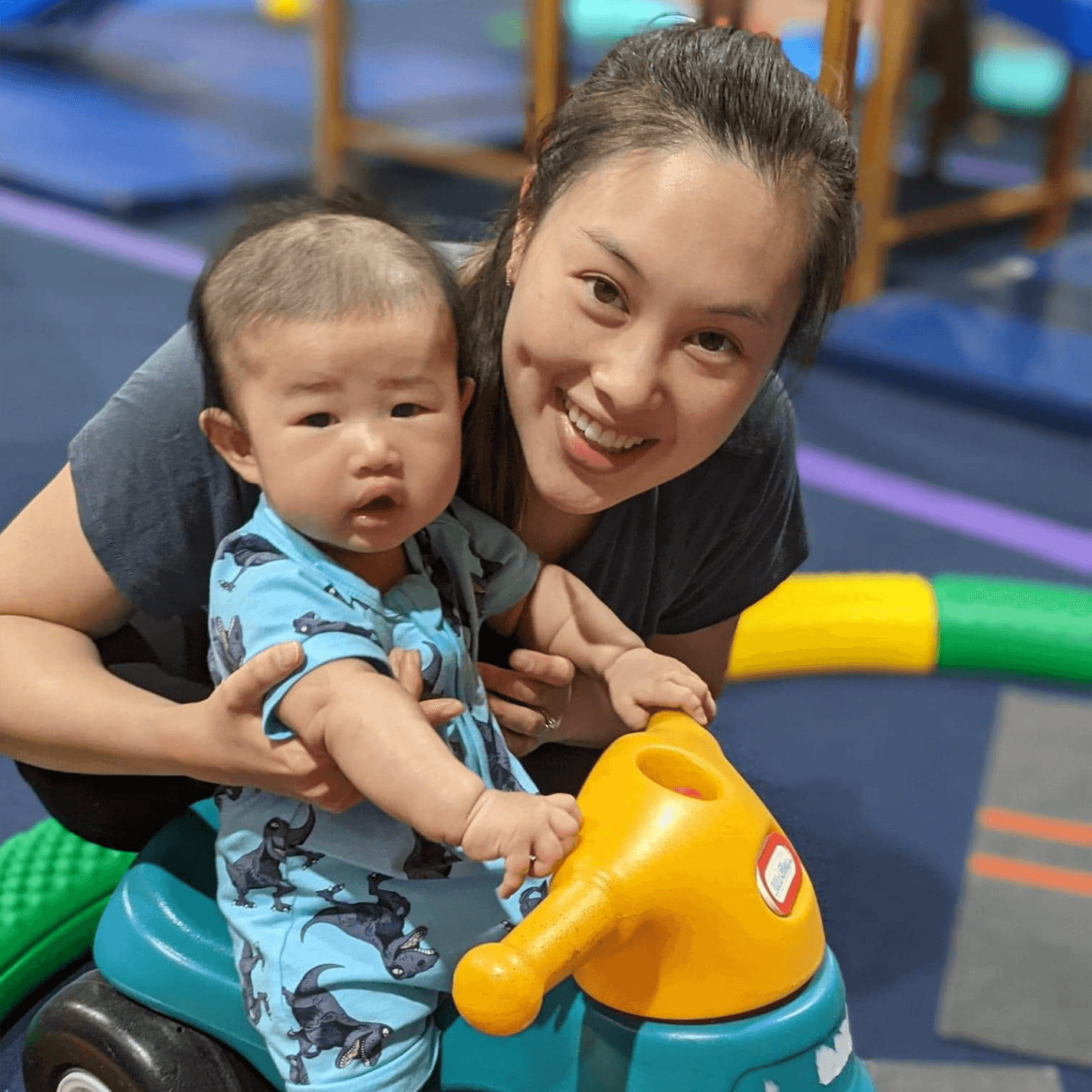 A mother holding her baby and smiling at a KinderGym